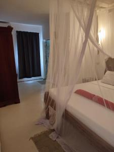 a bedroom with a bed with a mosquito net at GIORGIA HOUSE WATAMU BEACH in Watamu