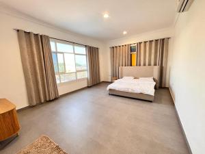 ein Schlafzimmer mit einem Bett und einem großen Fenster in der Unterkunft 4 Bedrooms villa for rent in Al Ḩamīdīyah
