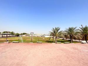 einen Park mit Bänken und Palmen auf einem Feld in der Unterkunft 4 Bedrooms villa for rent in Al Ḩamīdīyah