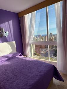 a bedroom with a purple bed and a large window at Neptuno View 22 in Benidorm