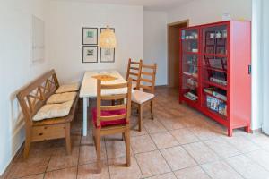 une salle à manger avec une table, des chaises et une armoire rouge dans l'établissement Ferienhaus Bettina, à Dornumersiel