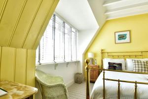 a bedroom with a bed and a desk and a window at Lulworth Cove Inn in Lulworth Cove