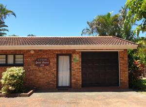 a brick building with a garage and palm trees at Grace Avenue Bungalow in Port Edward +9 photos