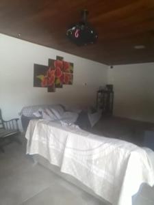 ein Schlafzimmer mit einem weißen Bett und Gemälden an der Wand in der Unterkunft Recanto Verde in Maricá