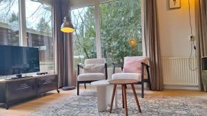 オッテルローにあるBungalow De Beuk 6p kindvriendelijkのリビングルーム(椅子2脚、薄型テレビ付)