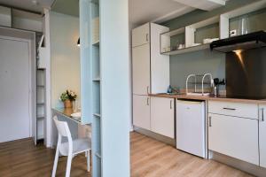 a kitchen with white cabinets and a table and a chair at Lille Train station nice studio in Lille