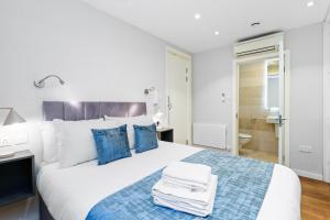 a bedroom with a large white bed with blue pillows at Urban Nest 2 in London