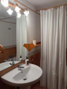 baño con lavabo y cortina de ducha blanca en Apartamentos Nevados 24610, en Benasque