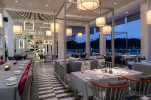 a restaurant with white tables and chairs and windows at The Nai Harn in Nai Harn Beach