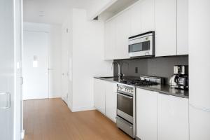 een witte keuken met een fornuis en een magnetron bij FiDi 1BR w Gym WD nr S St Seaport NYC-536 in New York