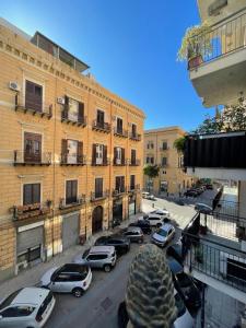 una strada di città con auto parcheggiate di fronte agli edifici di Palazzo Gallo a Palermo