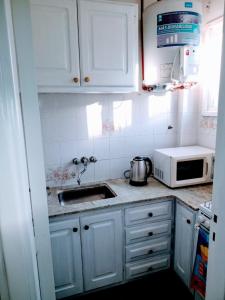 uma cozinha com armários brancos, um lavatório e um micro-ondas em Depto a mts de la playa zona Güemes/Shopping Aldrey em Mar del Plata