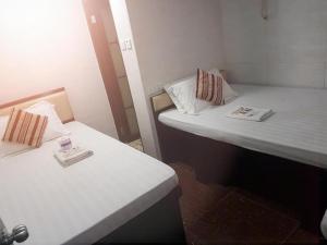 2 camas en una habitación pequeña con sábanas blancas en Crystal Hostel, en Hong Kong