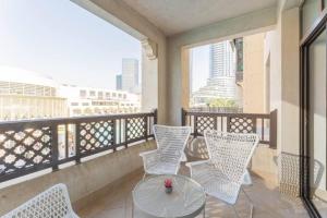 d'un balcon avec des chaises blanches et une table en verre. dans l'établissement Traditional 2 Bedroom with Dubai Fountain View, à Dubaï