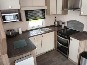 a small kitchen with a sink and a stove at Lovely Caravan At Hoburne Bashley, New Forest District! Ref 97166s in New Milton