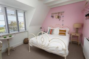 a bedroom with a white bed and a pink wall at Lulworth Cove Inn in Lulworth Cove