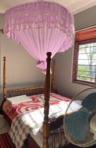 a bedroom with a bed with a canopy and a chair at Henotes B&B in Kamuli