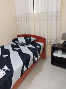 1 dormitorio con 1 cama con edredón blanco y negro en ALOJAMIENTO EDUCOL, en Moyobamba