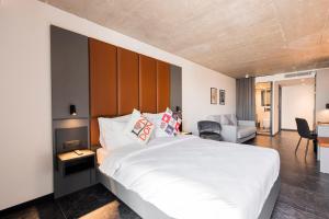 a bedroom with a large white bed and a chair at The Londoner Hotel St. Julian's in St. Julianʼs