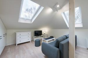 ein Wohnzimmer mit einem blauen Sofa und 2 Fenstern in der Unterkunft DR Apartments - Seadream in Sopot