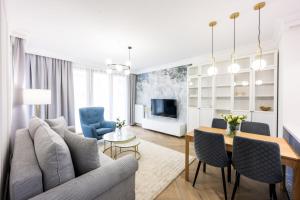 een woonkamer met een bank en een tafel en stoelen bij Native Apartments Orawska 14/127 in Krakau