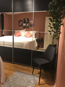 1 dormitorio con cama, silla y espejo en Top floor apartment in Stavangers best area! en Stavanger