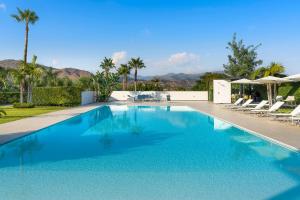 une piscine avec des chaises, des arbres et des montagnes en arrière-plan dans l'établissement Villa Greta, à Fiumefreddo di Sicilia