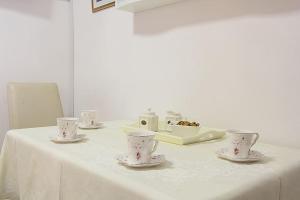 a white table with cups and saucers on it at Apartment Kovac Old Town 2 in Dubrovnik