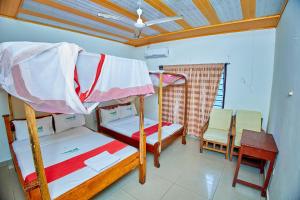 2 Etagenbetten in einem Zimmer mit einem Tisch und Stühlen in der Unterkunft Diani Home Stays in Diani Beach