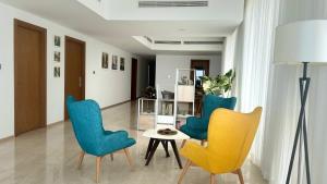 uma sala de estar com cadeiras azuis e amarelas e uma mesa em Altair Luxury Colombo by Miracle em Colombo