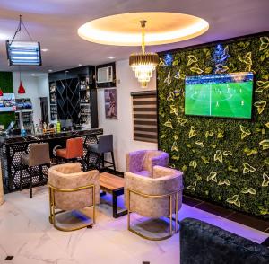 a bar with chairs and a tv on a wall at Chillers Hotel and Suites in Aiyetoto-Asogun
