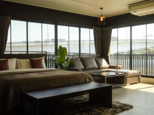 バンコクにあるNORN Riverside Bangkok Hotel - นอนริมน้ำのベッドルーム1室(ベッド1台、ソファ、窓付)