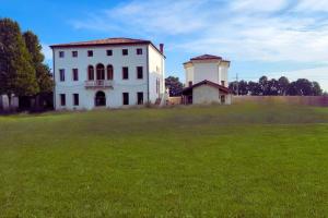 een groot wit huis in een grasveld bij enJoy Home - Villa Ca' Dura in Ronchi di Campanile