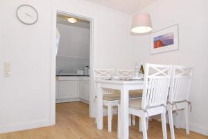 uma sala de jantar branca com uma mesa e cadeiras brancas em Olympia Haus 1, Whg 3 em Westerland