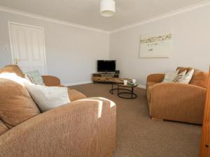 a living room with two couches and a tv at Sandy Toes in Swanage