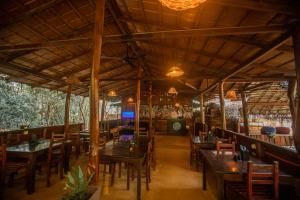 un restaurante con mesas de madera y sillas en una habitación en INN On The Tree Eco Resort Sigiriya, en Sigiriya