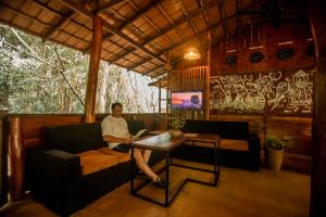 un hombre sentado en un sofá en una habitación con una mesa en INN On The Tree Eco Resort Sigiriya, en Sigiriya