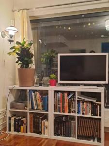a television on a white book shelf with books at Central Cozy 2BDR Getaway Sauna Free Park + Wi-Fi in Helsinki