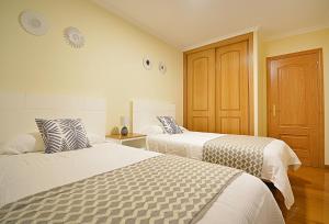 a bedroom with two beds and a wooden door at GALIHOST - Maravilloso apartamento en Combarro in Combarro