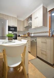 a kitchen with wooden cabinets and a white table and chairs at GALIHOST - Maravilloso apartamento en Combarro in Combarro +21 photos