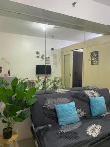 a living room with a black leather couch with blue pillows at Sea Residences in Manila