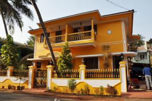 una casa amarilla con una valla delante de ella en Minria Guest House, en Benaulim