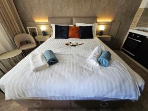 uma grande cama branca com toalhas e almofadas em AGAPE Apartment em Podgorica