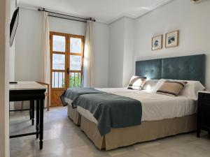 a bedroom with a large bed and a desk at Hotel Maestre in Córdoba
