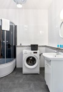 a white bathroom with a washing machine and a sink at Zawady Comfort Apartment in Poznań
