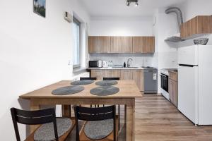 Zawady Comfort Apartment في بوزنان: مطبخ مع طاولة خشبية وبعض الكراسي