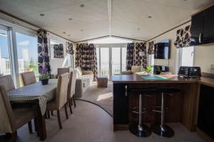 cocina y sala de estar con mesa y sillas en Stunning Caravan With Full Sea Views At Hopton Haven Ref 80044s en Great Yarmouth