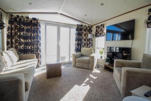sala de estar con sofá, sillas y TV en Stunning Caravan With Full Sea Views At Hopton Haven Ref 80044s en Great Yarmouth