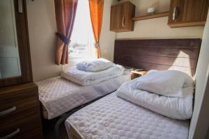 2 camas en una habitación pequeña con ventana en Stunning Caravan With Full Sea Views At Hopton Haven Ref 80044s en Great Yarmouth