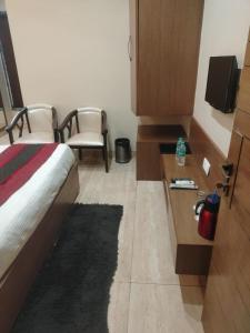 Habitación de hotel con cama, escritorio y sillas en Hotel the Mansion , Mathura en Mathura